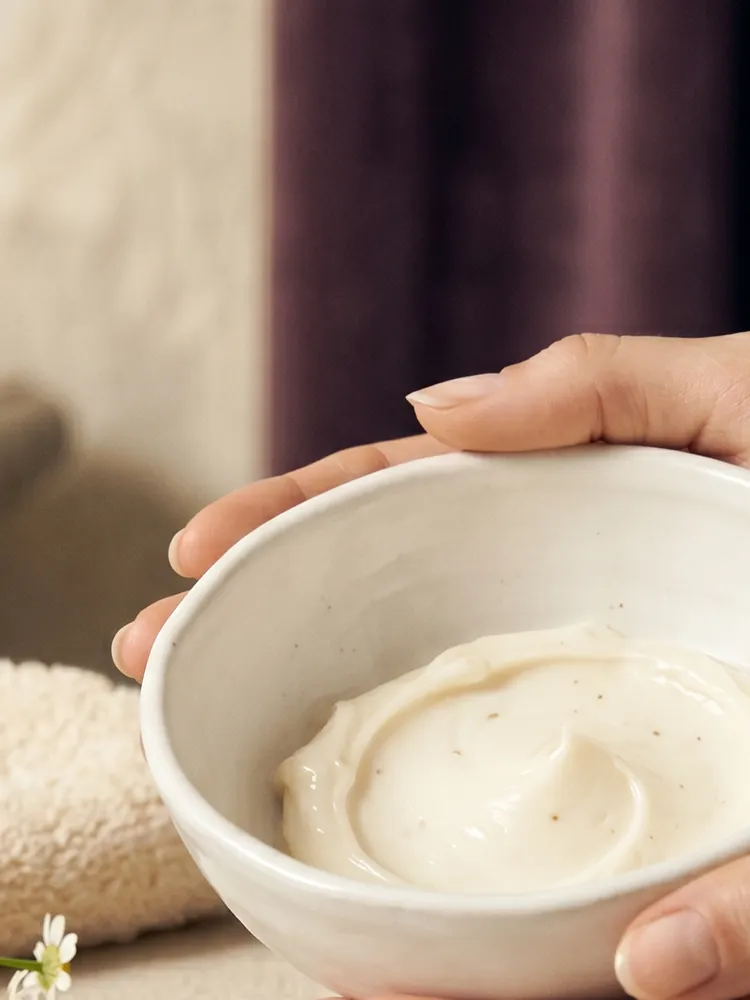 Mani che tengono una ciotola di crema durante la routine skincare