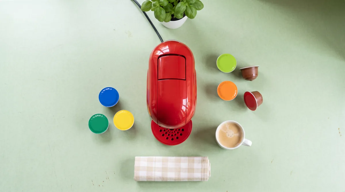Macchina da caffè a capsule Nescafé Dolce Gusto compatta su un piano di cucina chiaro, con tazzina in erogazione